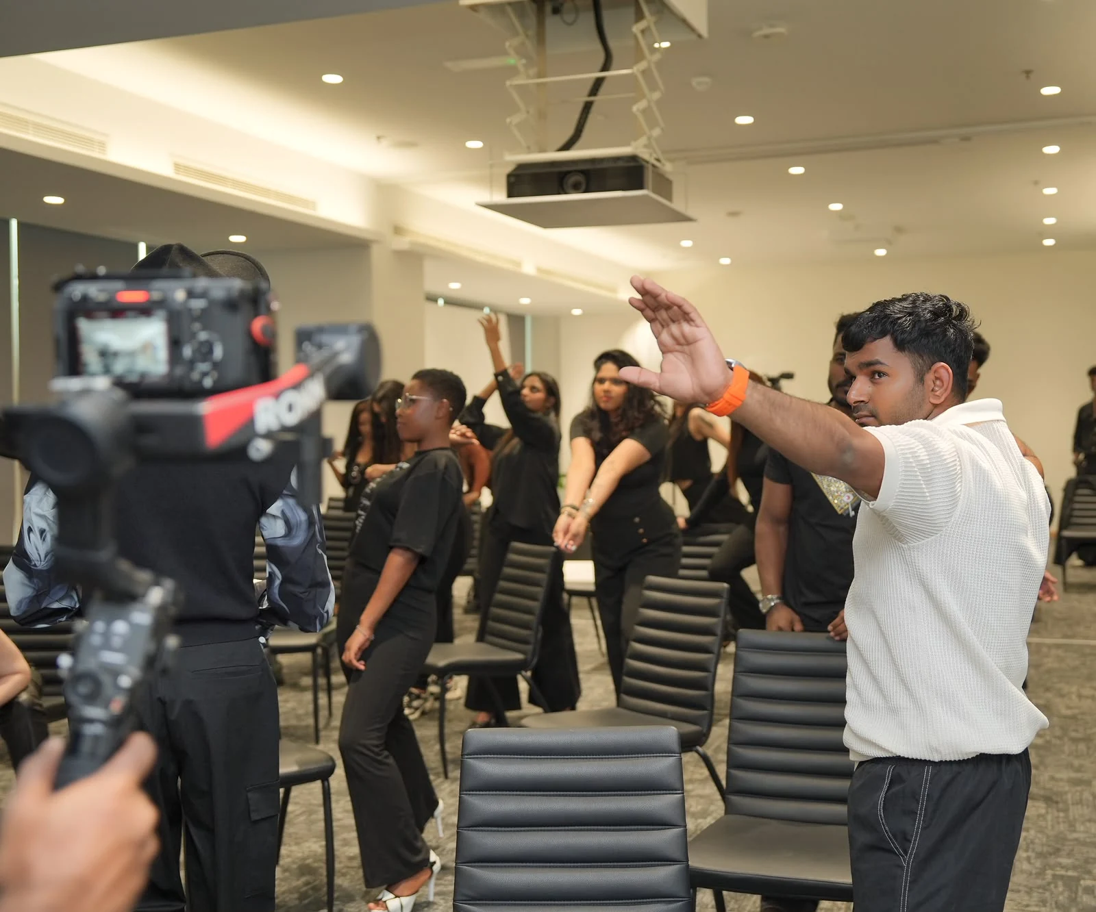 A camera crew filming models practising coordinated movement in class.