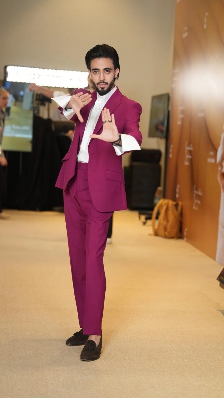 A model demonstrating an expressive pose in a burgundy suit.
