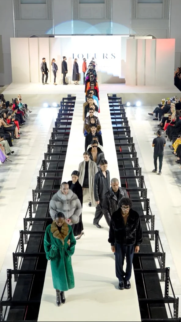 A procession of models walking the runway at a fashion show.
