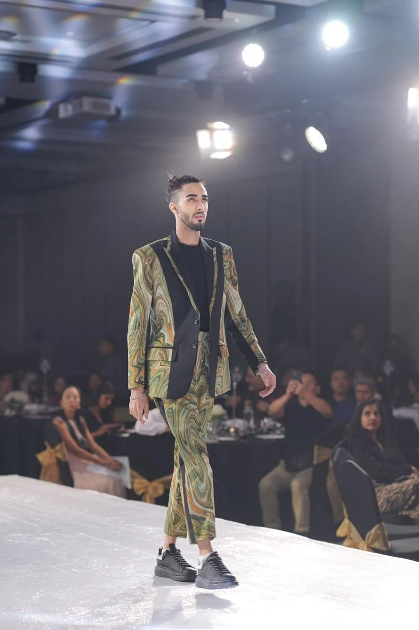 A model walking the runway in a green patterned suit.